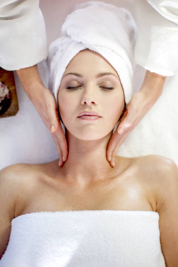 Young woman lying on massage table receiving beauty treatment